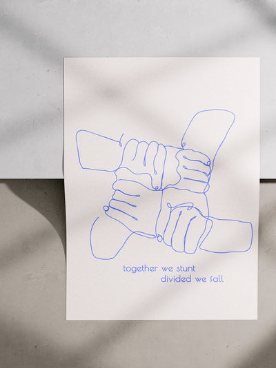 Poster liegt auf einer Kante. Es handelt sich um einen Betonboden mit Stufe. Im Bild sieht man moody Schatten. Auf dem Poster ist das Motiv: Die Handhaltung Basketkreuz von zwei Personen als sogenannte One-Line Zeichnung. Der Hintergrund ist Offwhite und die Linie der Zeichnung Blau. Unten drunter ist geschrieben: together we stunt divided we fall.