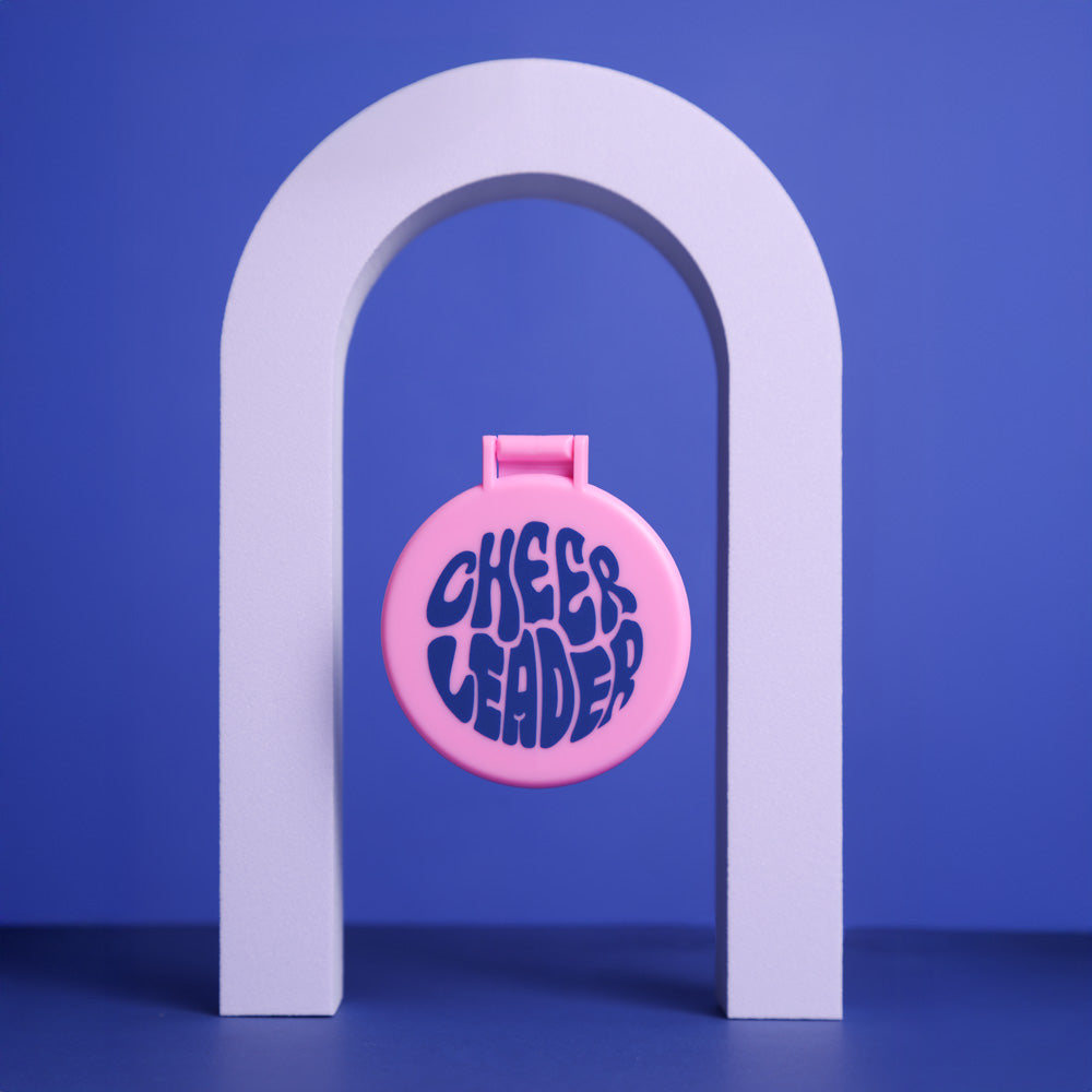 Cheerleader Handspiegel aufklappbar in Rosa zum Aufstellen auf blauem Hintergrund, unter einem Bogen, zugeklappt, schwebend