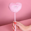 Stift mit Plüschherz auf dem ein silberner Metallaufnäher dran ist mit der Aufschrift: Cheerleader. in der Variante Rosa. Der Stift wird von einer Hand mit orangefarbenem Nagellack gehalten. Der Hintergrund ist rosa.