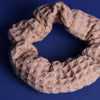 Scrunchie in Cappuccino Farbton mit 3-D Waffelmuster liegt auf blauem Hintergrund.
