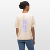 Eine dunkelhäuftige, weiblich gelesene Person mit einem lockigen Zopf trägt ein beiges Shirt mit dem Motiv: COUNT. Das Oversized Organic T-shirt hat die Farbe natural raw. Auf dem Shirt ist das Motiv: ready,set, 5,6,7 and 8,1,2,up zu sehen. Zudem trägt die Person eine Jeanshose und steht vor weißem Hintergrund.