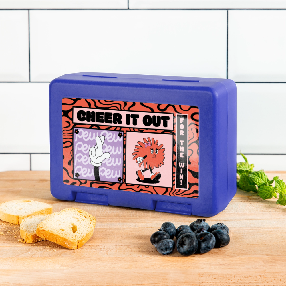 Cheerleader Lunchbox in royal blue steht vor weißem Hintergrund auf weißem Untergrund. Auf der Dose ist ein Comicmitiv mit der Aufschrift: Cheer it out for the Win auf einem rot schwarzem Muster. Außerdem sieht man hier einen Pompom mit Armen und Meinen und Haarschleife, wie auch Augen. Die Pompomfigur pfeift. Zudem gibt es noch eine Comichand mit gekreuzten Fingern. Die Dose steht auf einem Holzhintergrund vor einer weißen Fliesenwand. Auf der Holzarbeitsfläche sind Zwieback, ein paar Blaubeeren und Minze.