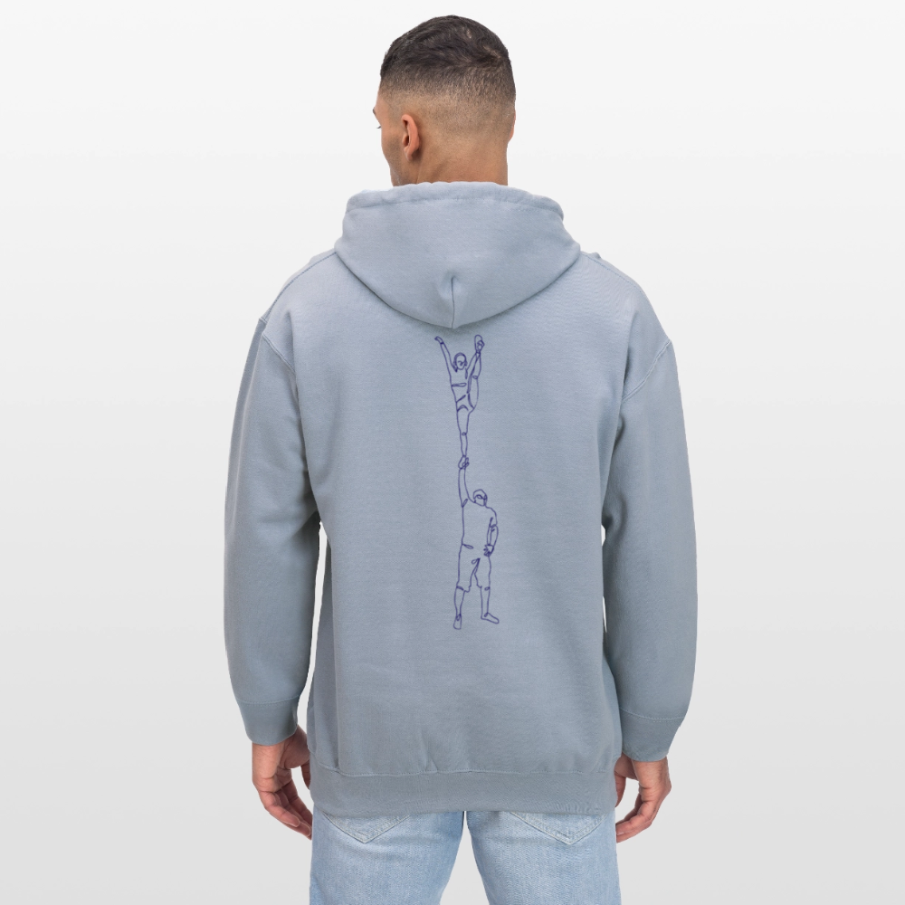 Ein mänlich gelesene Person trägt hier einen Hoodie mit dem Motiv: One Line Partnerstunt Scorpion in hellem blau. Die Person trägt eine Jeanshose und hat dunkle, kurze Haare. Sie steht vor einer weißen Wand.