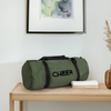 Sporttasche in Khaki mit grauen Griffen und der schwarzen Aufschrift Cheer. Die Tasche liegt auf einem Holz-Sideboard. Daneben liegen Handtücher. Rechts steht eine Vase im Anschnitt und oben hängt ein Bild im Anschnitt. Die Tasche ist beidseitig bedruckt. 