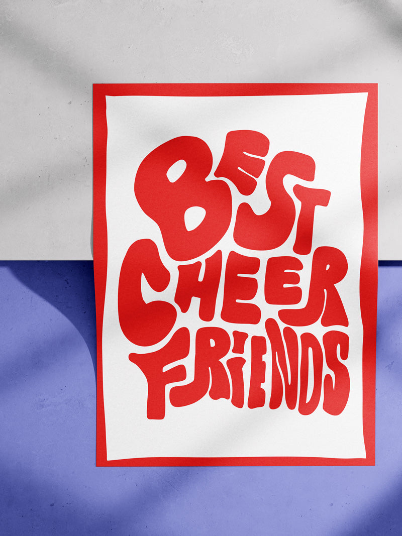Poster liegt auf einer Kante. Es handelt sich um einen Betonboden mit Stufe. Im Bild sieht man moody Schatten. Auf dem Poster ist das Motiv: "Best Cheer Friends" in rot mit rotem Rand. 