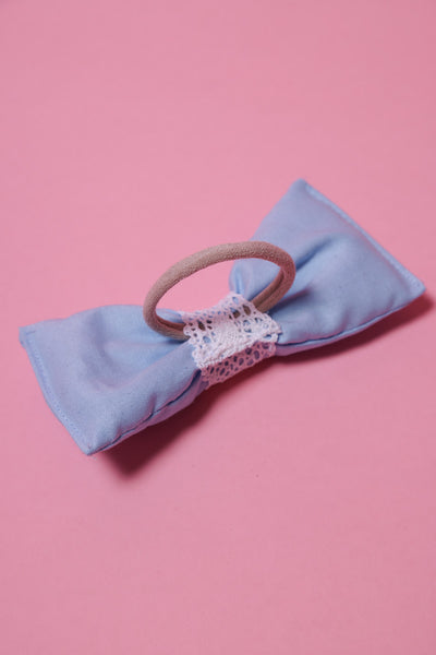 Hellblaue gepolsterte Schleife mit beiger Vintagespitze ist hier mit einem beigen Haargummi auf rosa Hintergrund zu sehen. Man sieht hier die Rückseite der Schleife.