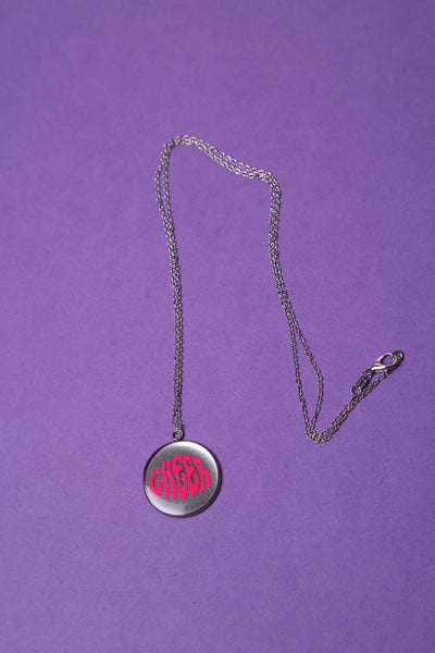 Cheerleader Medaillon in 925er Silber Kette und Edelstahl Anhänger, der mit dem Schriftzug Cheer versehen ist und Epoxidharz beinhaltet liegt auf einem lila Hintergrund.