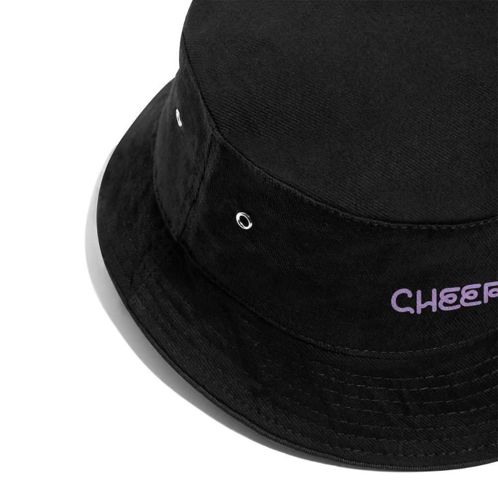 Zu sehen ist ein Bucket Hat in schwarz mit dem Aufdruck:  Cheer in einer Detailaufnahme. Der Hut ist angeschnitten und verschwindet in der oberen rechten Ecke.
