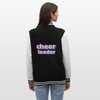 Collegejacke in Schwarz -weiß mit Lila,rosa,weißer pixelart Aufschrift: Cheerleader. Die Bündchen sind alle Schwarz-weiß gestreift. Die von einer dunkelhaarigen Frau getragene Jacke ist auf weißem Hintergrund zu sehen. Man sieht hier die Rückseite. Die Frau trägt dazu eine Jeanshose.
