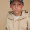 Zu sehen ist ein Cheerleader Pixelart Motiv auf einer Relaxed Vintage Cap in der Farbe vintage black. Diese wird getragen von einem Junior Jungen, der einen beigen Pullover trägt und vor beigem Hintergrund steht.