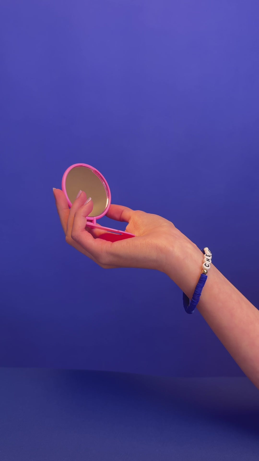 Handspiegel mit der Aufschrift Cheerleading geöffnet und geschlossen in einer Hand auf blauem Hintergrund.

Hand mirror with the inscription Cheerleading opened and closed in one hand on a blue background.